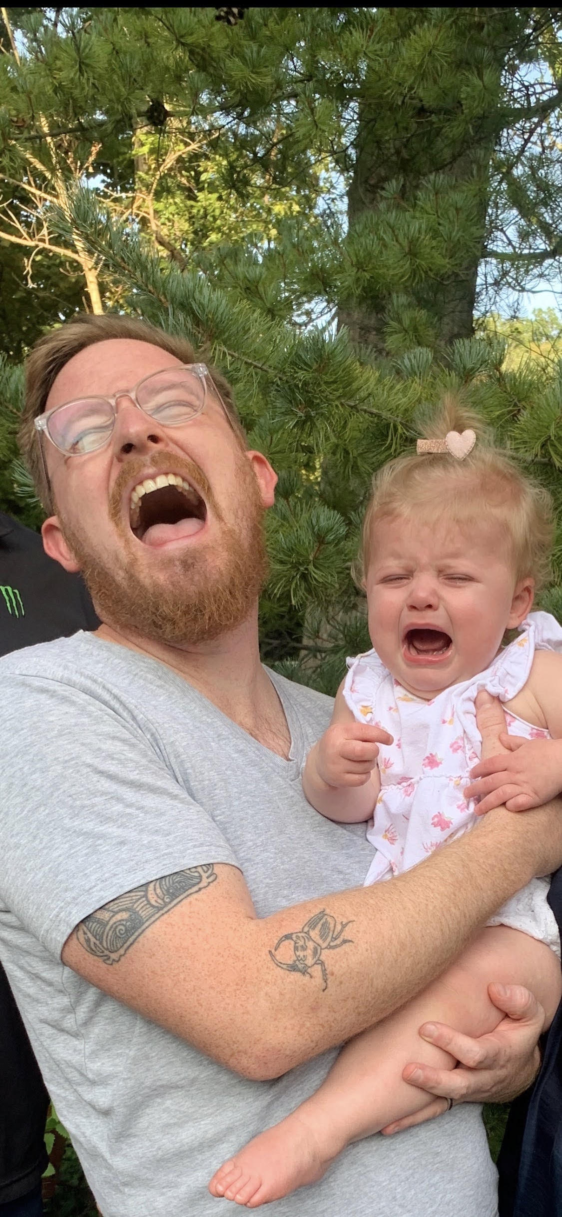Dan and his baby daughter outdoors, both crying with their mouths wide open